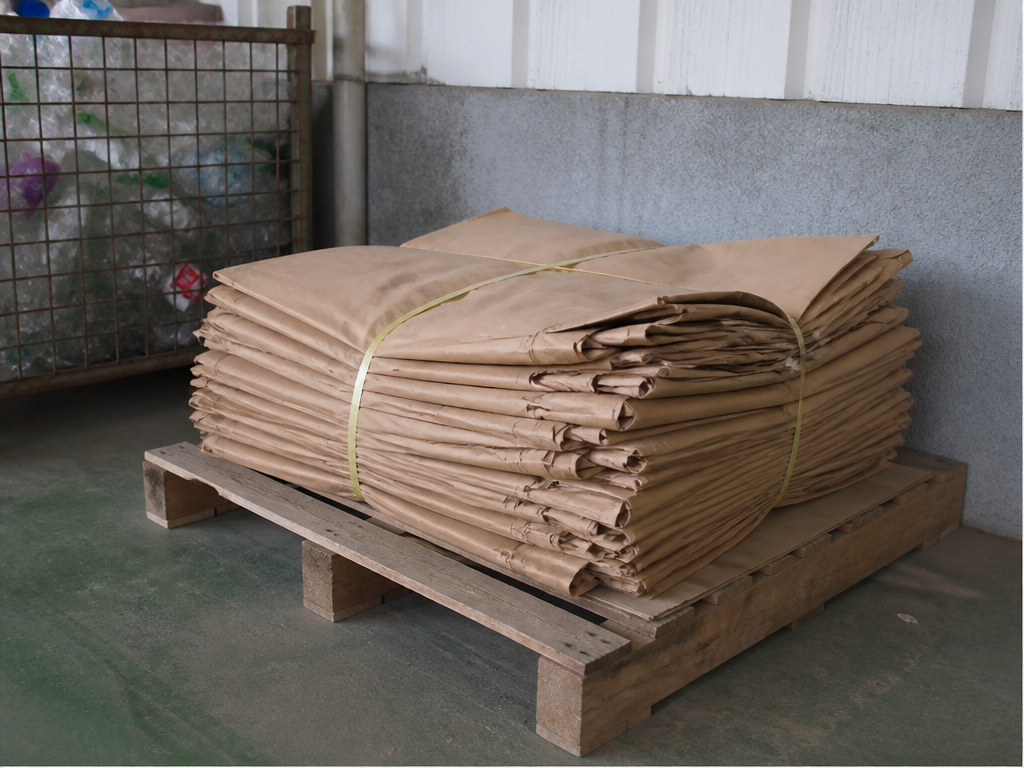 Avant le recyclage des sacs en papier, des sacs kraft vides, attachés et aplatis, posés sur une palette dans le coin de recyclage de l'usine